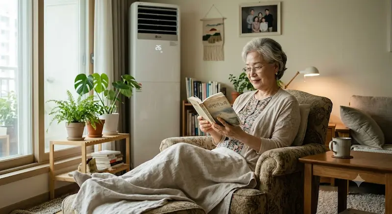 얇은 겉옷을 입고 에어컨 26도 실내에서 편안하게 앉아 있는 시니어 여성